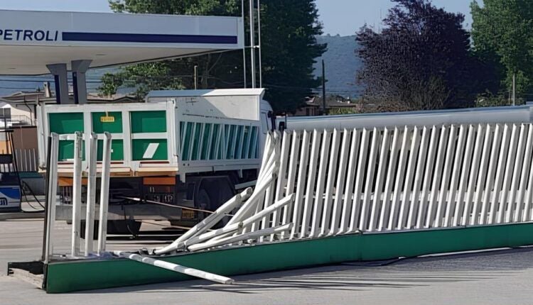 Un ponte stradale con la barriera laterale gravemente danneggiata e deformata. Sullo sfondo si vede un camion fermo e, oltre gli alberi, un rilievo montuoso.