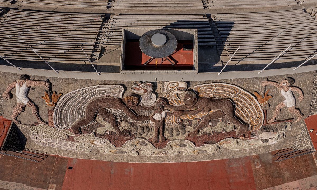 Veduta dall’alto del rilievo monumentale di Diego Rivera sulla parete inclinata dello Stadio Olimpico Universitario dell’UNAM. L’opera, realizzata con pietre di diversi colori, raffigura al centro un’aquila con le ali spiegate, affiancata da figure umane e motivi simbolici.